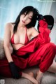 A woman in a red dress sitting on a couch.