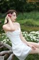 A woman in a white dress sitting on a tree branch.