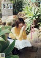 A woman sitting on a rock next to a cactus.