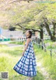 A woman in a blue and white dress standing in a field.