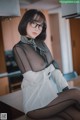 A woman wearing glasses sitting on a kitchen counter.