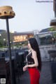 A woman in a black top and red skirt posing for a picture.