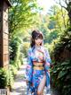 A woman in a blue kimono is walking down a path.