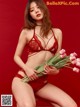 A woman in a red lingerie holding a bunch of flowers.