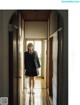 A woman in a school uniform standing in a hallway.