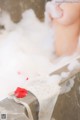 A woman taking a bath in a bathtub filled with foam.