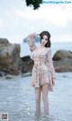 A woman in a pink dress standing in the water.